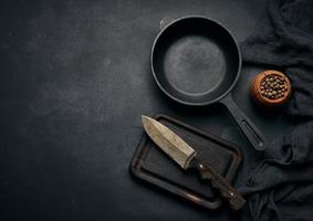 Empty round cast iron frying pan with wooden handle on black table, top view photo