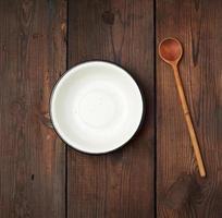 empty round metal white plate and wooden spoon on the table photo