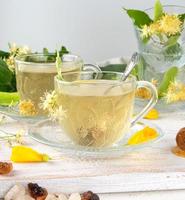 transparent cup with tea from linden on a white wooden board photo