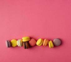 round multi-colored baked macarons with cream lie in a line photo