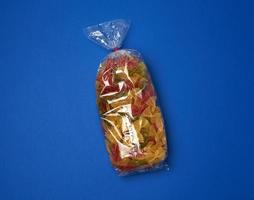 transparent cellophane bag with raw colorful pasta in the form of bows photo