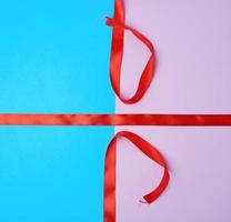 red satin ribbon on a colored background photo