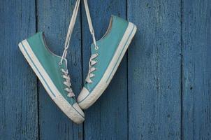 Turquoise youth sneakers hanging on a nail photo