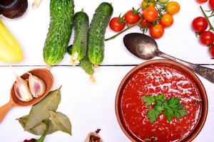 Fresh gazpacho soup in a brown ceramic dish with a spoon photo