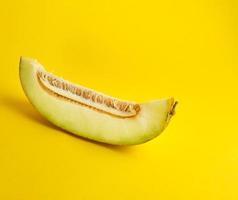 piece of ripe melon with seeds on a yellow background photo