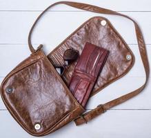 open brown leather bag with purse and glasses photo