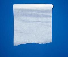papel para hornear de pergamino blanco desenrollado sobre un fondo azul foto