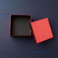 caja de cartón cuadrada roja vacía abierta sobre un fondo de madera azul foto