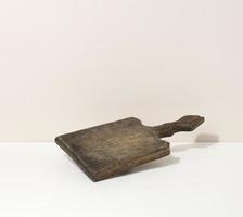 tablero de cocina de madera marrón vacío rectangular sobre una mesa blanca, utensilios. lugar para exhibir comida foto