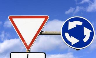 two road signs against a blue sky with white clouds photo