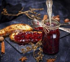 raspberry jam with a glass jar and slices of white bread photo