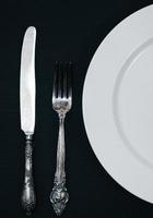 Half empty white plates, vintage knife and fork on  table photo