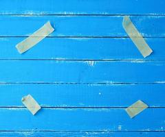 cuatro trozos de papel amarillo de cinta adhesiva pegados en las esquinas sobre un fondo de madera azul foto