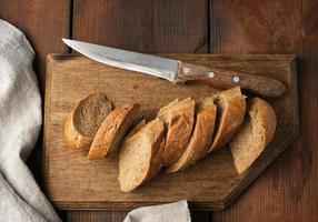 sliced rye flour baguette on a wooden cutting board photo