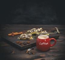 coffee with marshmallow in a red ceramic mug on a brown board and chocolate biscuits photo