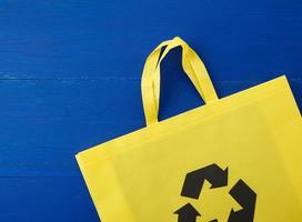 Reusable yellow viscose bag on blue wooden background photo