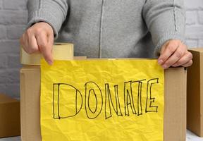 woman in a gray sweater holds a crumpled yellow sheet of paper with the inscription photo