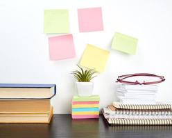 stack of spiral notebooks and colored stickers, next to a ceramic pot with a flower photo