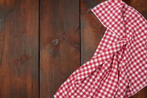 toalla de cocina a cuadros rojos blancos sobre un fondo de madera marrón foto