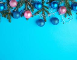 burning multi-colored light bulbs on a garland with a white cable and green twigs of needles photo