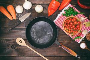empty black round frying pan and fresh vegetables photo