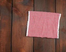 toalla de cocina a cuadros rojos blancos sobre un fondo de madera marrón foto