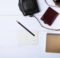 empty paper postcards and a black wooden pencil on a white wooden background, beside a brown leather purse photo