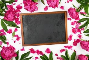 empty black frame for writing in chalk and blooming red peonies photo