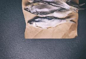 whole dried fish in the roach scales lying on brown paper photo