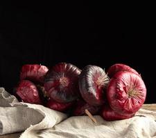 round red onion in husk on a gray linen napkin, black background photo
