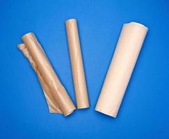 three rolled rolls with brown parchment baking paper on a blue background photo