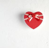 closed red heart-shaped box on a white textured surface photo