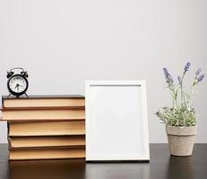 empty white photo frame, stack of books and a pot of growing lavender