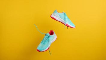 pair of textile blue sneakers with laces levitate on a yellow background. Shoes for sports, jogging photo
