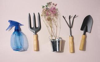 Garden tools, shovel, rake and fork on a beige background, top view. photo