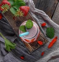 homemade smoothie from yogurt and fresh strawberries in a glass jar, top view photo