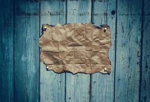 Brown rumpled kraft paper hanging on a blue wooden surface photo