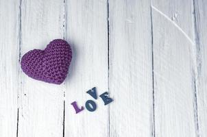 small red heart with the word love on a white wooden surface photo