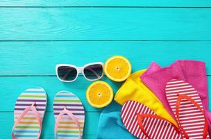Colorful flip flops, sunglasses and oranges on blue wooden background. Top view and copy space. Summertime photo
