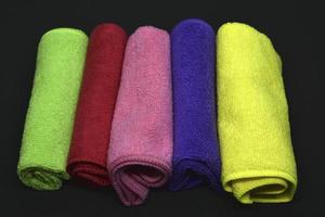 Multicolored towels on a black background. Terry towels. Colored rags in rolls. Rolled-up rags. photo