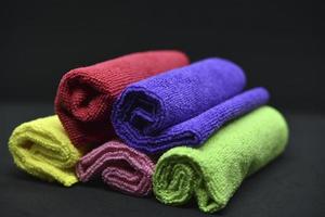 Multicolored towels on a black background. Terry towels. Colored rags in rolls. Rolled-up rags. photo