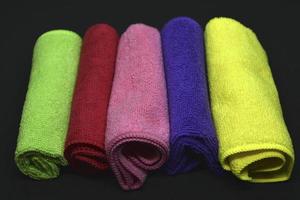 Multicolored towels on a black background. Terry towels. Colored rags in rolls. Rolled-up rags. photo