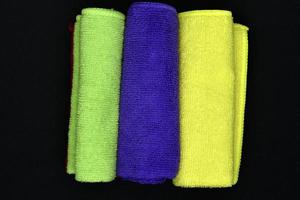 Multicolored towels on a black background. Terry towels. Colored rags in rolls. Rolled-up rags. photo