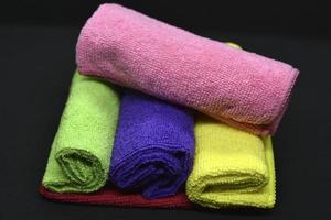 toallas multicolores sobre un fondo negro. toallas de felpa. trapos de colores en rollos. trapos enrollados. foto