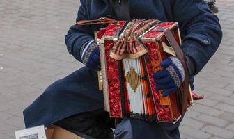 Close-up of a man's hand playing button accordion outdoors in winter. photo