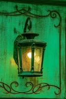 Lamp light on the wall. Antique iron lantern on the wall outside. Garden metal electric lamp. Outdoor wall lamp. photo