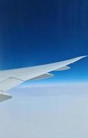 vista desde un avión hacia el ala y las nubes debajo. foto