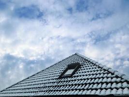 ventana de techo abierta en estilo velux con tejas negras cubiertas de nieve blanca foto