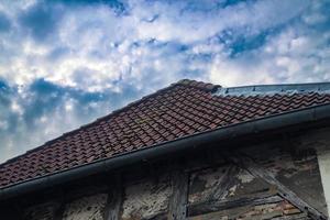 Old roof with black roof tiles with half timebered walls photo