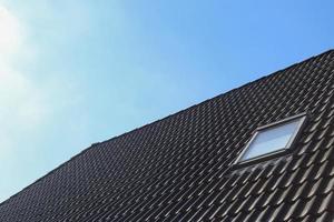 ventana de techo de estilo velux con tejas negras.